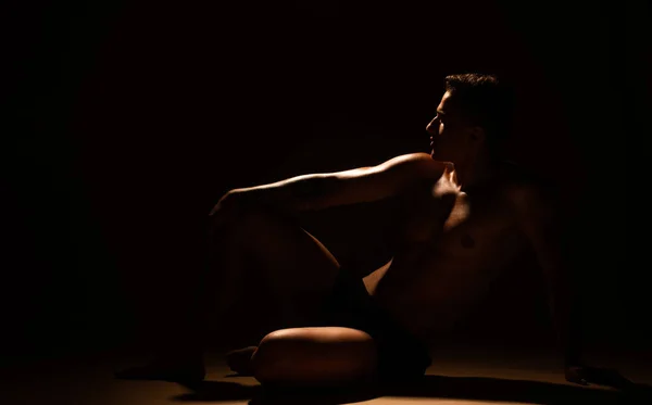 スタジオで床に座っているハンサムな男のシルエット — ストック写真