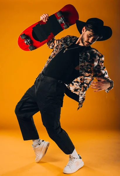 現代的な服でスケートボードとポーズハンサムなスタイリッシュな男の肖像画 — ストック写真