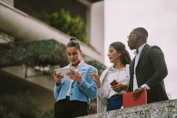 Trzech Biznesmenów Patrzących Tablet Stojąc Budynku — Zdjęcie stockowe