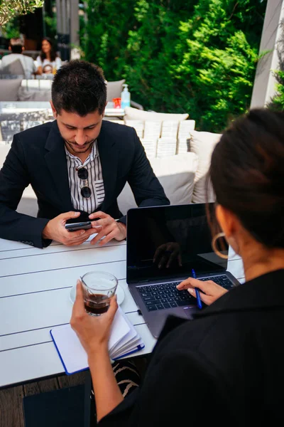一位女商人正在喝咖啡 在膝上型电脑上工作 而她的男同事则在手机上打滚 — 图库照片