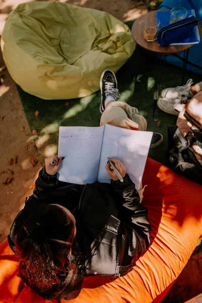 一个黑头发的高中女生正坐在懒洋洋的书包上做作业 — 图库照片