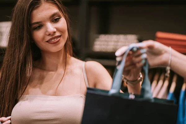 아름다운 소녀가 판매자에게서 쇼핑백을 가지고 모습을 자세히 들여다봄 — 스톡 사진
