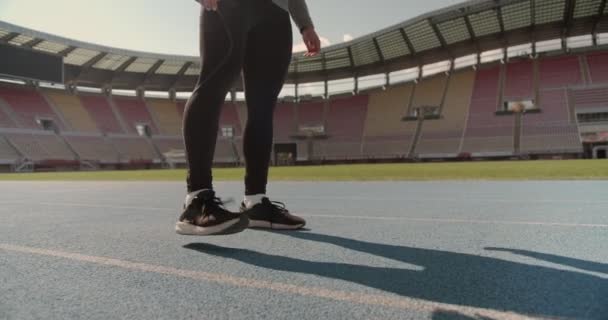 スタジアムで運動する準備をしている若い男が足を暖めて — ストック動画