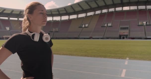 Женщина Фокусируется Упражнениях Стадионе Наушниках Бутылке Водой Движения Грузовиков — стоковое видео