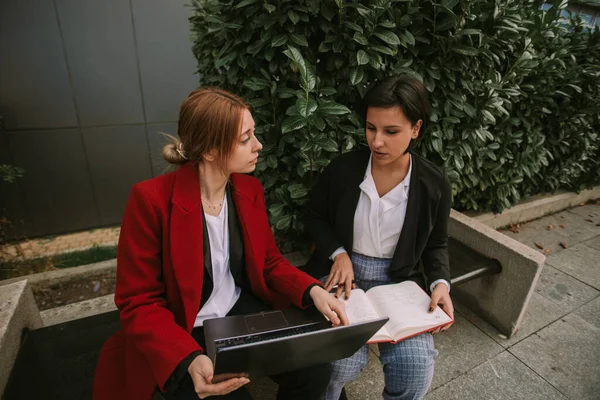Duas Mulheres Negócios Trabalhando Enquanto Sentam Banco Perto Prédio — Fotografia de Stock