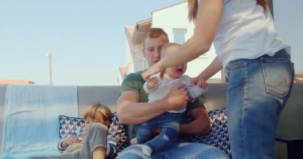 ハンサムな父親が泣いてる赤ん坊を妻に渡して息子を連れて行く間に — ストック動画