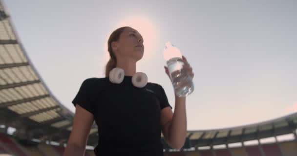 Chica Con Auriculares Beber Agua Durante Ejercicio Estadio — Vídeo de stock