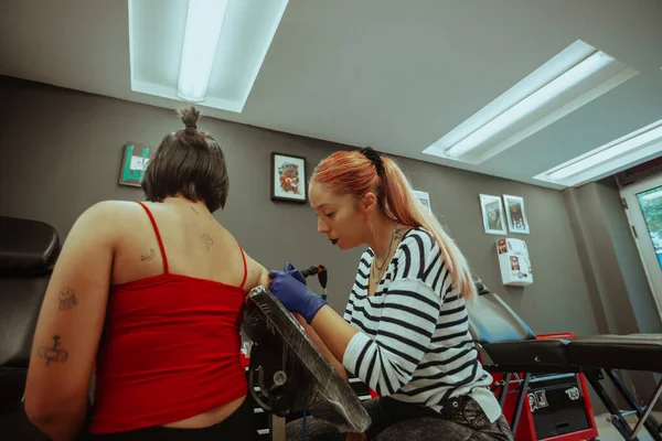 Татуировщица Татуирует Своего Клиента Сидя Студии — стоковое фото
