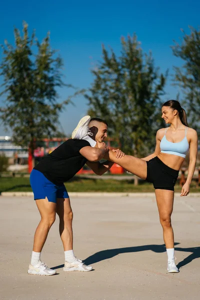 Мускулистый Спортсмен Помогает Своей Девушке Размять Ноги Спорт Открытом Воздухе — стоковое фото