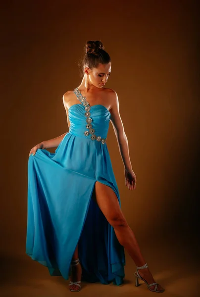 青いドレス姿でポーズをとりながら見下ろしている魅力的な女の子 セクシー脚区別 — ストック写真