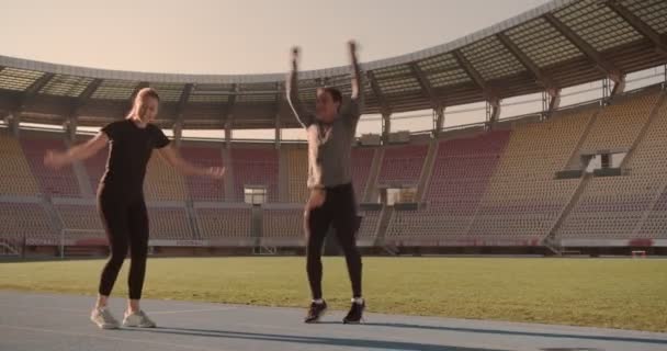 Two Young People Doing Jumping Jacks Stretching Muscles Run Stadium — Video Stock