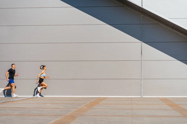 Full length photo of two athletes, a couple, running in a row together on a beautiful sunny day