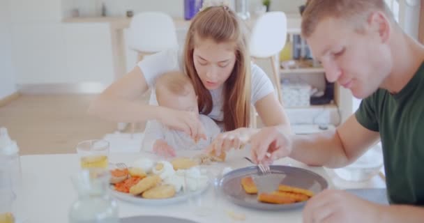 Zbliżenie Pięknych Rodziców Rozmawiających Sobą Podczas Jedzenia Małymi Dziećmi Siedząc — Wideo stockowe