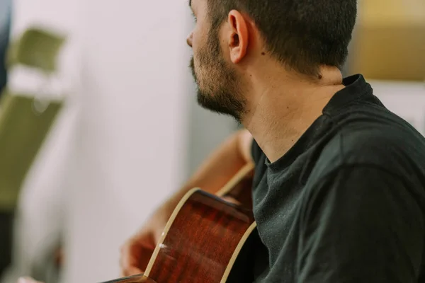 A close up photo of handsome male person playing guitar for his colleagues at work