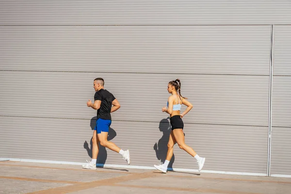Fit athletes, male and female, jogging in a row outside on a beautiful sunny day