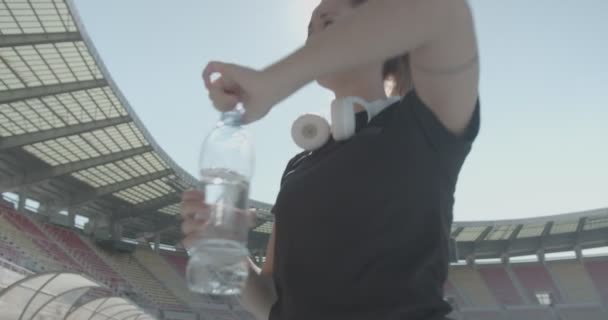Menina Com Fones Ouvido Beber Água Durante Exercício Estádio — Vídeo de Stock