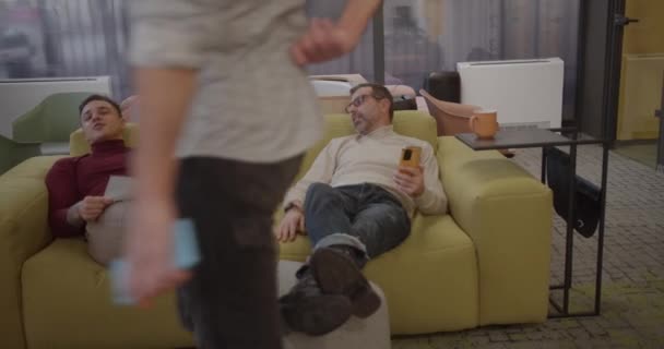 Male Colleagues Joined Another Colleague While Resting Cozy Office Sofa — Vídeos de Stock