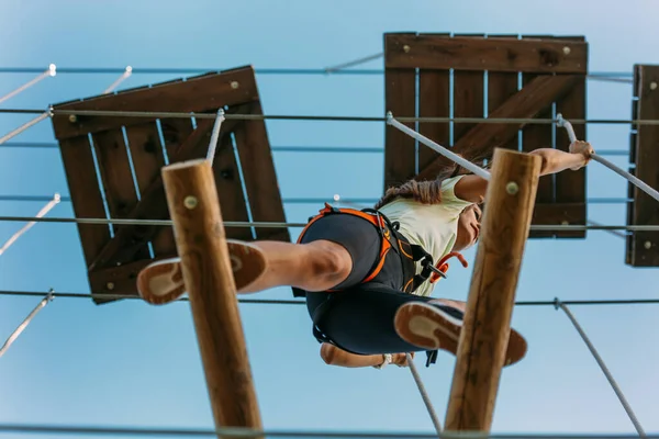 stock image Young girl in sportswear walking on planks high up in the air in the adventure park
