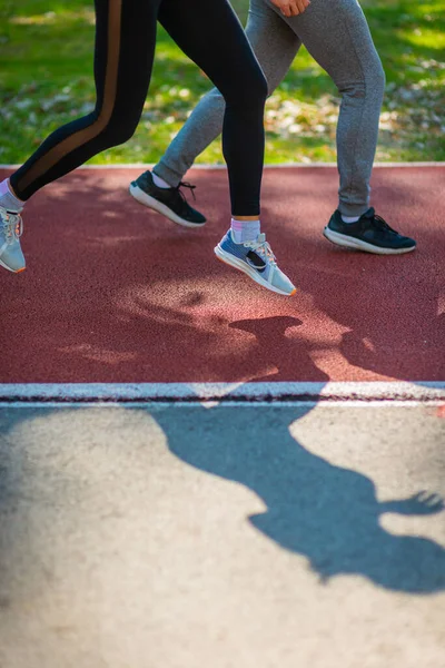 赤いスポーツコースを走る男女の足の写真 — ストック写真