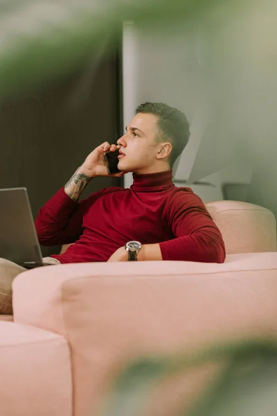 A side view photo of young male business person looking at something while having a phone call