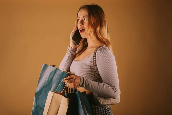 美女拿着购物袋 一边打电话一边购物 — 图库照片