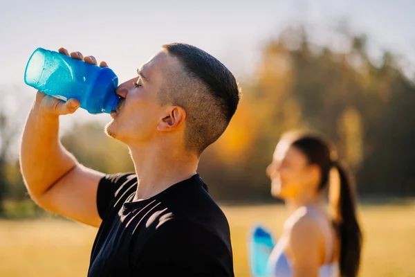 Male sports person drinking water after exercising