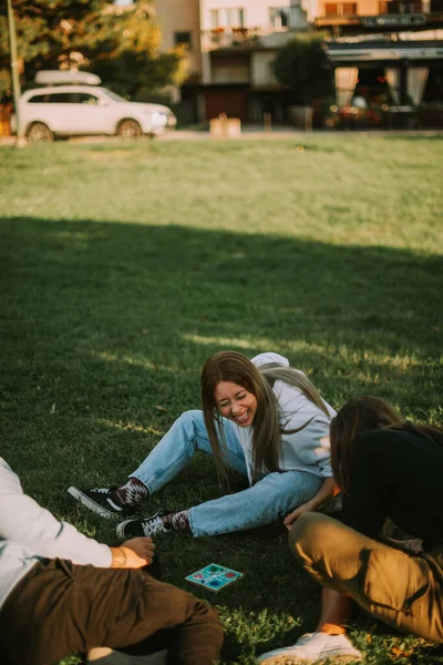 一个漂亮的金发姑娘坐在公园里和她的朋友们一起笑 — 图库照片