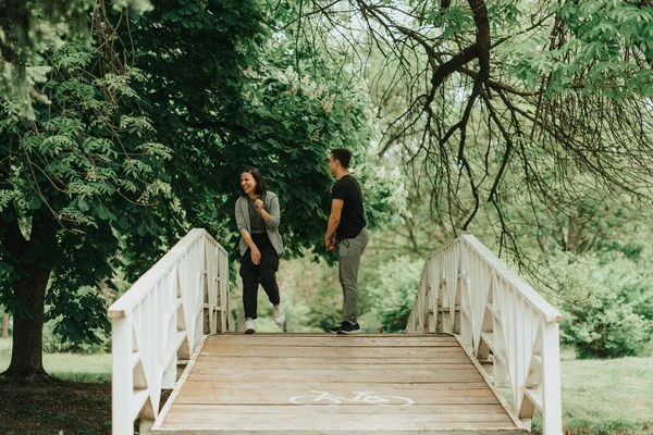这对可爱的夫妇站在公园的白桥上笑着 — 图库照片