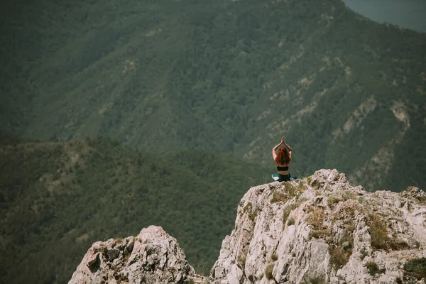 一个红头发的女孩坐在山顶上 胳膊上散满了红头发 — 图库照片
