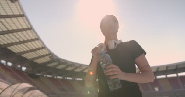 Menina Com Fones Ouvido Beber Água Durante Exercício Estádio — Vídeo de Stock