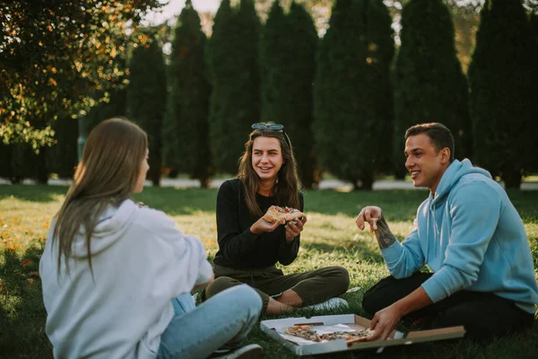 Tre Amici Che Parlano Mentre Mangiano Pizza Sull Erba Parco — Foto Stock
