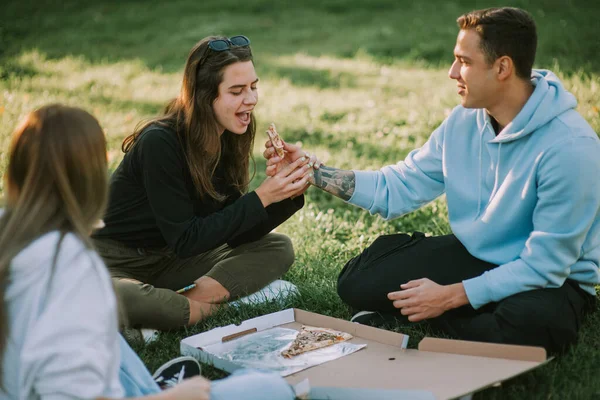 Bruneta Dívky Snaží Jíst Pizzu Plátek Chlapce Zatímco Sedí Parku — Stock fotografie