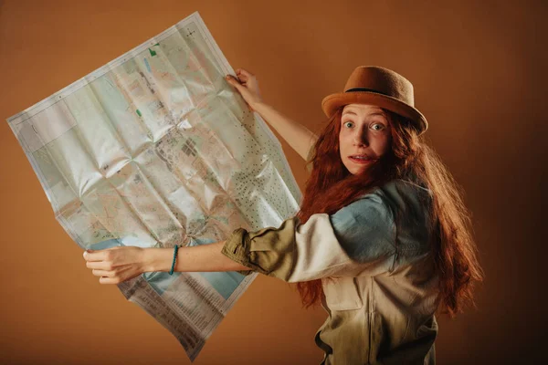 Beautiful travelermaking faces while standing at the studio and holding her map