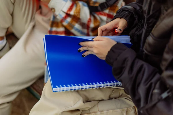女子高生がノートを開いている 彼女は友達と外で勉強しようとしてる — ストック写真