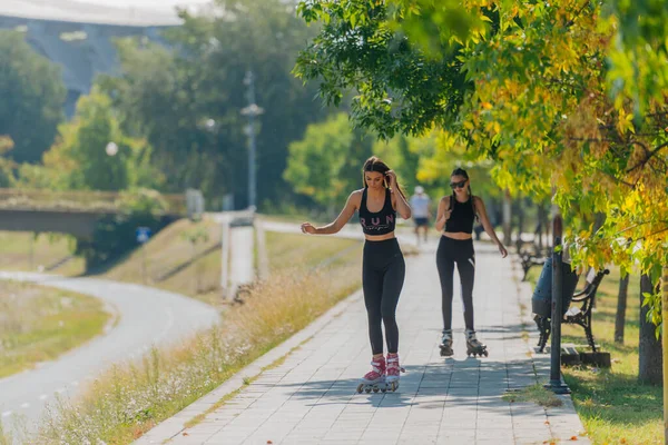 晴れた日に公園で2つの美しいスポーツ女性ローラースケート — ストック写真