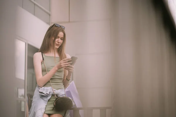 Hübsches Mädchen Schaut Auf Ihr Handy Während Sich Zaun Lehnt — Stockfoto