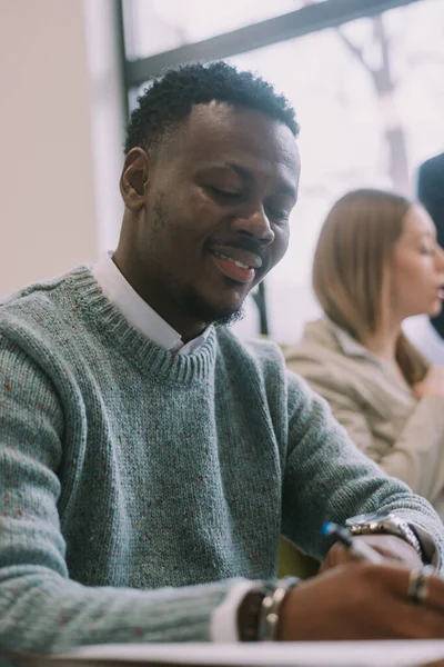 stock image Close up of handsome business man writting notes and smiling while sitting at the office