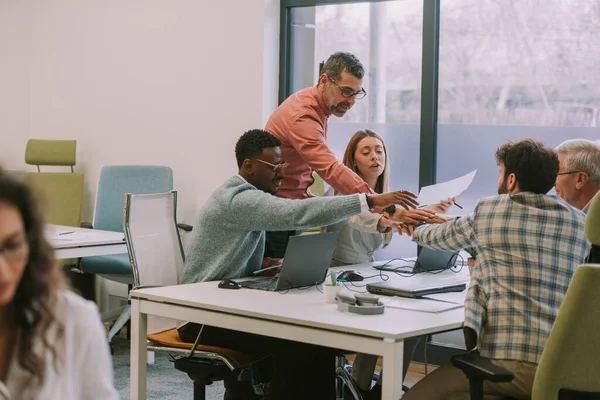 コワーキングスペースのオフィスデスクで手を携えているビジネス人のグループ — ストック写真
