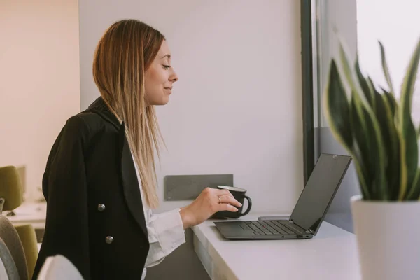 Güzel Sarışın Kadını Ofis Masasında Otururken Gülümsüyor Laptopuyla Çalışıyor — Stok fotoğraf