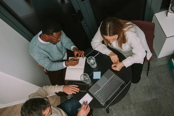 An above view photo of multiracial business coworkers writing notes for their new project at modern office