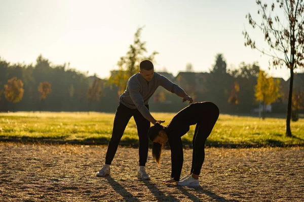 一位英俊的健身教练正在帮助他的客户进行热身运动 — 图库照片