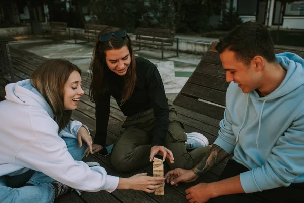 Τρεις Χαρούμενοι Φίλοι Διασκεδάζουν Παίζοντας Τζένγκα Και Καθισμένοι Στον Ξύλινο — Φωτογραφία Αρχείου