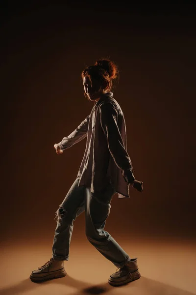 Silhouette of a ginger hair girl dancing while standing at the studio