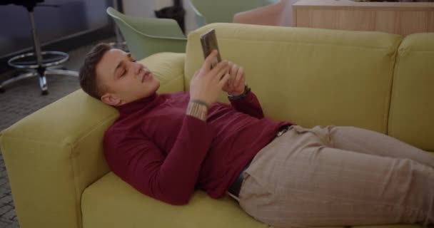Ofis Odasındaki Rahat Kanepede Dinlenen Genç Bir Işçi — Stok video