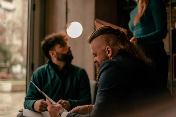 長い髪のビジネスマン彼らは会話をしている間 彼の後輩の同僚のプロジェクトソリューションをレビュー — ストック写真