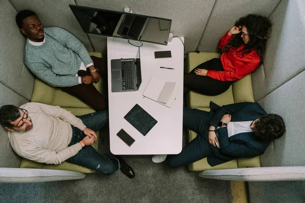 A high view photo of exhausted multiracial coworkers sleeping at the office