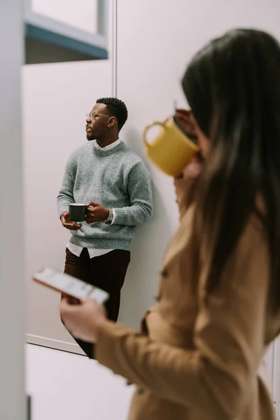 Νεαρή Μελαχρινή Πίνει Καφέ Στο Διάλειμμα Ενώ Μαύρος Συνάδελφος Ακούει — Φωτογραφία Αρχείου