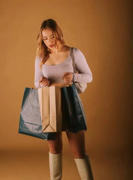 Csinos Lány Nézi Bevásárló Táskák Miközben Áll Stúdióban — Stock Fotó