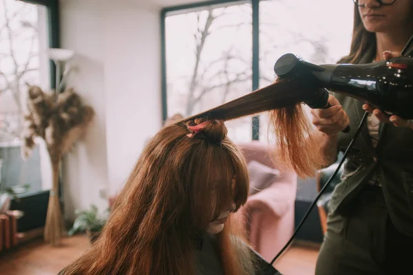 理发师站在理发店里吹干她客户的红头发 — 图库照片
