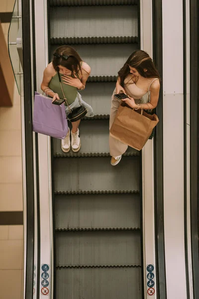 놀라운 소녀가 쇼핑몰 에스컬레이터로 내려가면서 핸드폰을 있습니다 — 스톡 사진